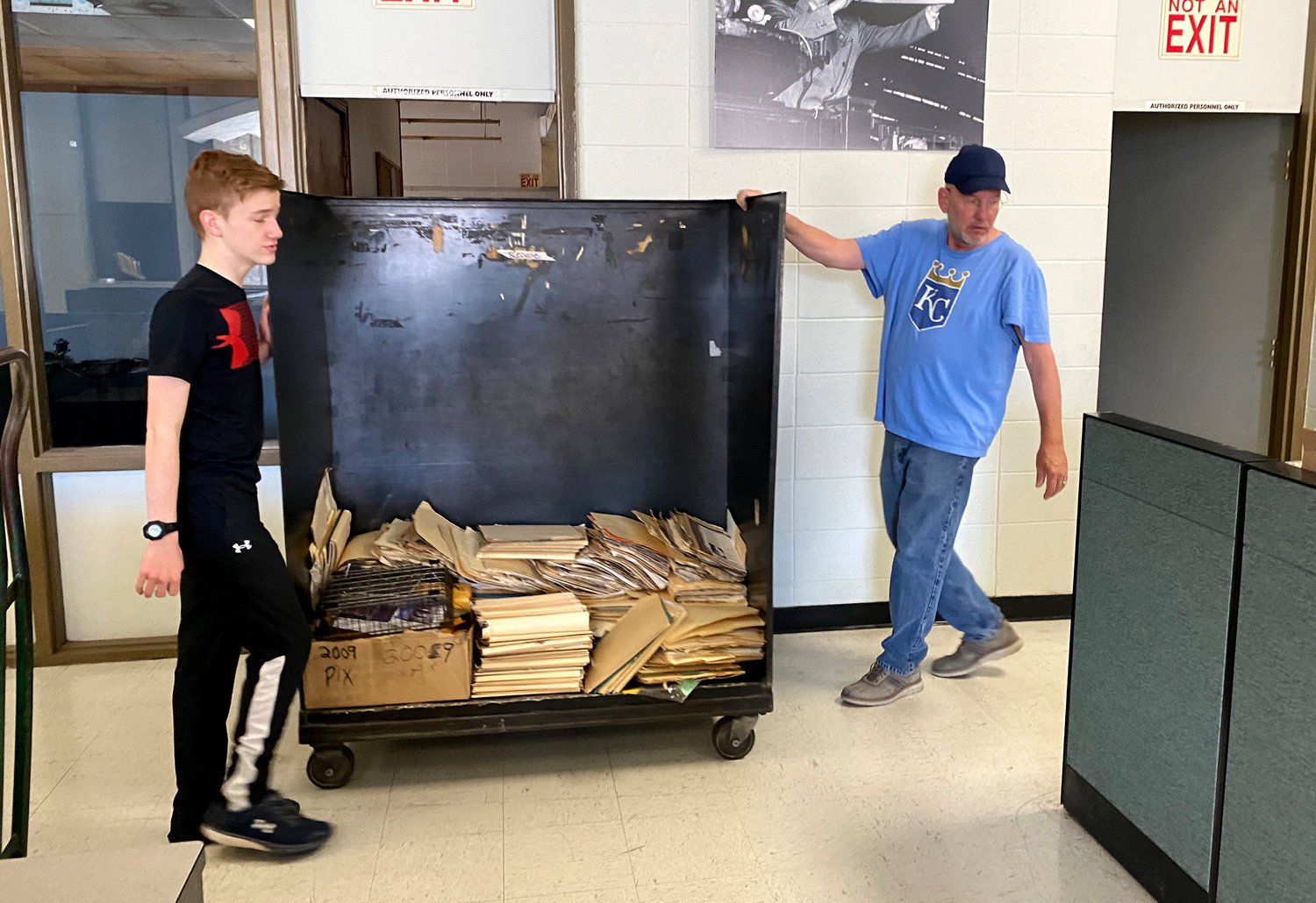 Democrat Reporter Chris Howell and his son move a cart full of old documents to be recycled during a clean-out of the office Saturday, March 26.